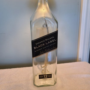 May include: A clear glass bottle with a black label that reads "JOHNNIE WALKER. BLACK LABEL. BLENDED SCOTCH WHISKY John Walker & Sons AGED 12 YEARS".