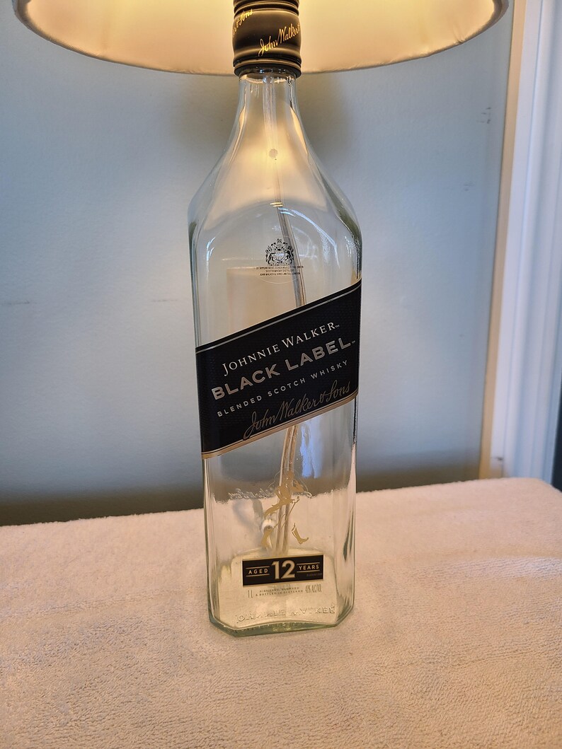 May include: A clear glass bottle with a black label that reads "JOHNNIE WALKER. BLACK LABEL. BLENDED SCOTCH WHISKY John Walker & Sons AGED 12 YEARS".