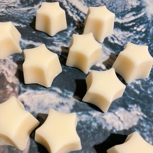May include: Ten white star-shaped wax melts on a marble surface.