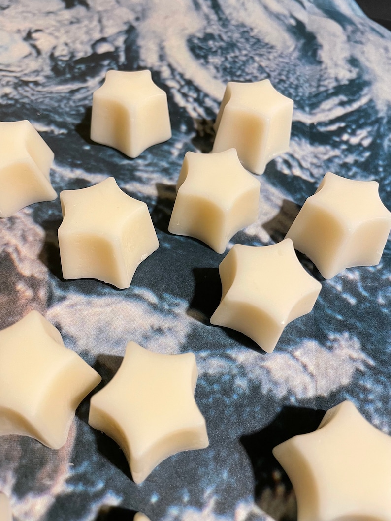 May include: Ten white star-shaped wax melts on a marble surface.