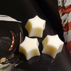 May include: Three white star-shaped wax melts on a black surface.