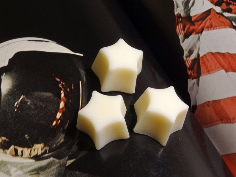 May include: Three white star-shaped wax melts on a black surface.