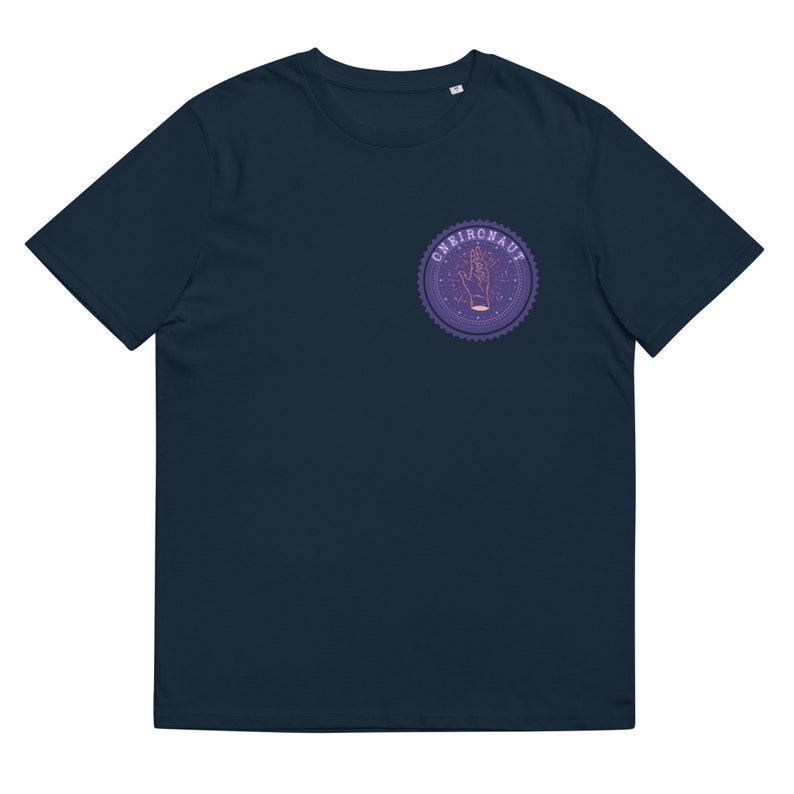 Op de afbeelding: Een marineblauw t-shirt met een paars en roze rond logo met een hand met sterren en de tekst "Oneironaut".