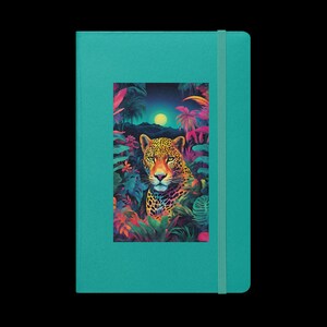 Könnte beinhalten: Ein türkisfarbenes Notizbuch mit einer farbenfrohen Illustration eines Jaguars in einer Dschungelkulisse. Der Jaguar blickt direkt auf den Betrachter mit einem Mond im Hintergrund.