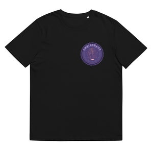 Op de afbeelding: Zwart T-shirt met een ronde grafische afbeelding in paars en roze met een hand met sterren en de tekst "Oneironaut".
