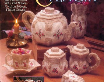 May include: A vintage tea set, hand-stitched with gold metallic cord on plastic canvas. The set includes a teapot, creamer, sugar bowl, cup and saucer, and a vase. The text reads "Collector's TEA SET".