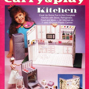 May include: A pink and purple plastic canvas doll kitchen set with a refrigerator, stove, and accessories. The set includes the text "Fashion Doll Carry & Play Kitchen". A young girl is holding the kitchen set.