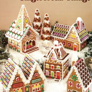Puede incluir: Un kit de manualidades de lona de plástico colorido titulado "Gingerbread Village" de Carol Mansfield. La imagen presenta varios modelos de casas de jengibre con diseños detallados, incluyendo tejados coloridos, ventanas y acentos decorativos. Las casas están ambientadas en un fondo festivo.