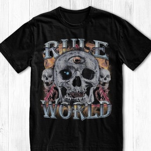 May include: Black t-shirt with a graphic print of a skull with a third eye and the text "RULE WORLD" in a vintage style.