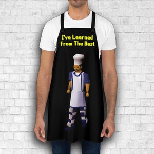 K&ouml;nnte beinhalten: Schwarze Sch&uuml;rze mit einer wei&szlig;en Kochfigur, die einen wei&szlig;en Hut und eine blau-wei&szlig; gestreifte Hose tr&auml;gt. Der Text "I've Learned From The Best" ist in Gelb auf der Sch&uuml;rze aufgedruckt.