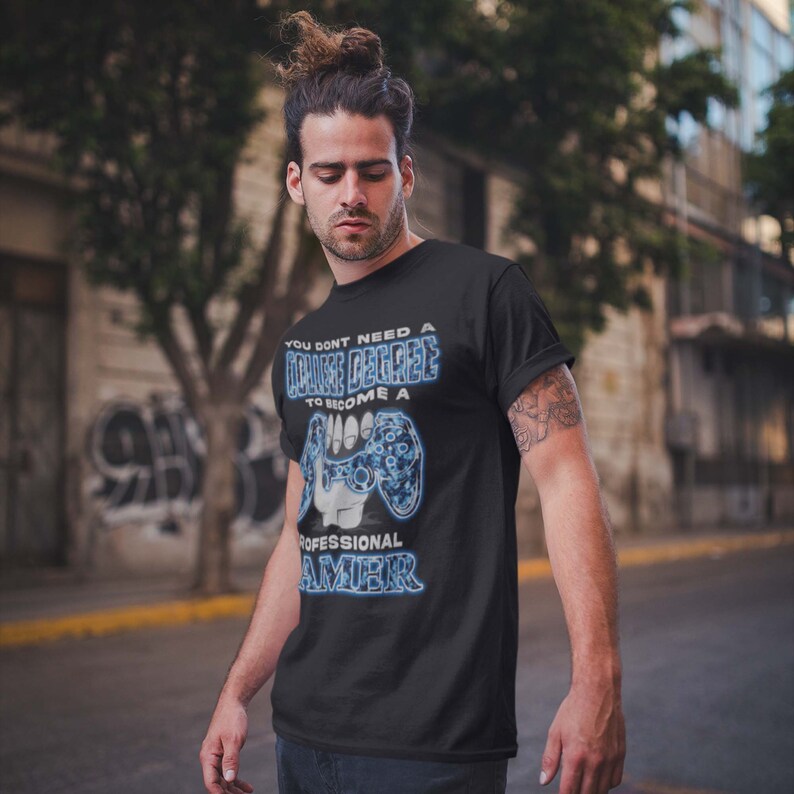 May include: A black t-shirt with a blue and white graphic of a video game controller. The text on the shirt reads "You don't need a college degree to become a professional gamer."