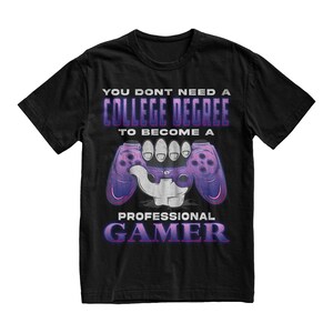 May include: Black t-shirt with a purple and white graphic of a hand holding a video game controller. The text on the shirt reads "You don't need a college degree to become a professional gamer."