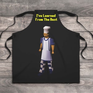 K&ouml;nnte beinhalten: Schwarze Sch&uuml;rze mit gelbem Text "I've Learned From The Best" und einer pixelartigen Kochfigur, die einen wei&szlig;en Kochhut, ein blaues Hemd, eine wei&szlig;e Sch&uuml;rze und eine karierte Hose tr&auml;gt.