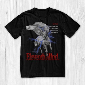 May include: Black t-shirt featuring a white winged horse graphic and the text "Eleventh Mind" in red. The text "M.I.N.D" is also on the shirt with the text "THE MIND IS ITS OWN PLACE AND IN ITSELF CAN MAKE A HEAVEN OF HELL AND A HELL OF HEAVEN".