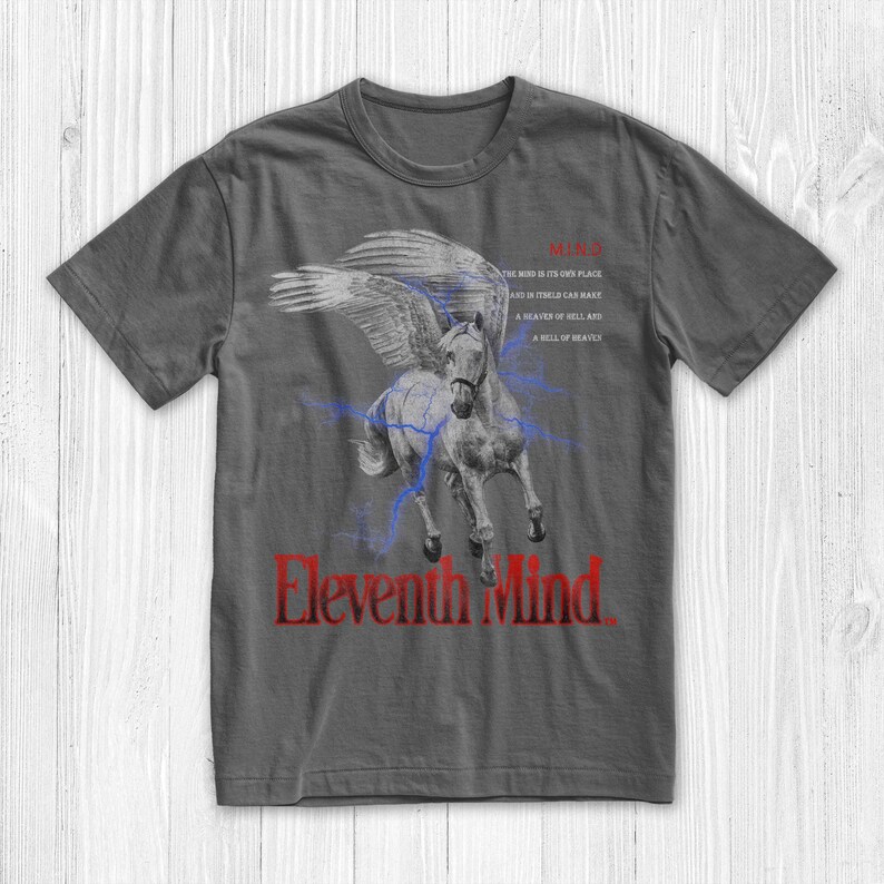 May include: A dark grey t-shirt featuring a red and white graphic of a winged horse with lightning bolts. The text "Eleventh Mind" is printed in red below the horse. The text "MIND" is printed in red at the top of the shirt, with a quote about the mind in smaller red text below it.