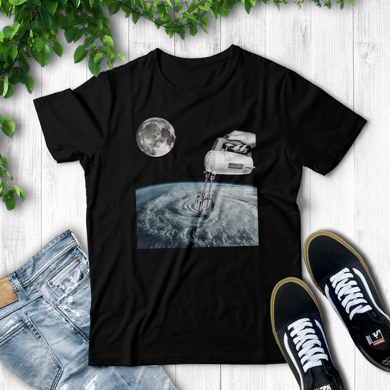 May include: A black t-shirt with a graphic of a hand holding a kitchen mixer over a swirling storm cloud and the moon in the background.