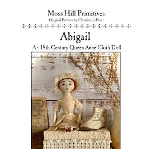 Può includere: Una bambola di stoffa in stile vintage di nome Abigail, vestita con un abito bianco e seduta su una pila di scatole con bordi in pizzo. La bambola ha un semplice berretto bianco e tratti dipinti. La bambola è una bambola di stoffa in stile Queen Anne del XVIII secolo.