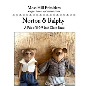 May include: Two handmade cloth bears, Norton and Ralphy, are sitting on a fabric background. The bears are 8 and 9 inches tall and are wearing clothes. The bear on the left is wearing a white shirt and blue pants. The bear on the right is wearing a gray shirt and white and black striped pants.