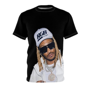 May include: Black t-shirt featuring a portrait of a person wearing a white cap with "RGB Freight" printed on it, sunglasses, and jewelry. The person is wearing a white jacket. The t-shirt is a crew neck.