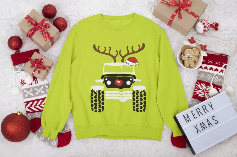Puede incluir: Un su&eacute;ter navide&ntilde;o verde lima con una silueta negra y blanca de un jeep. El jeep tiene una nariz roja y un gorro de Pap&aacute; Noel rojo en la parte superior. El jeep tiene cuernos y est&aacute; cubierto de nieve.