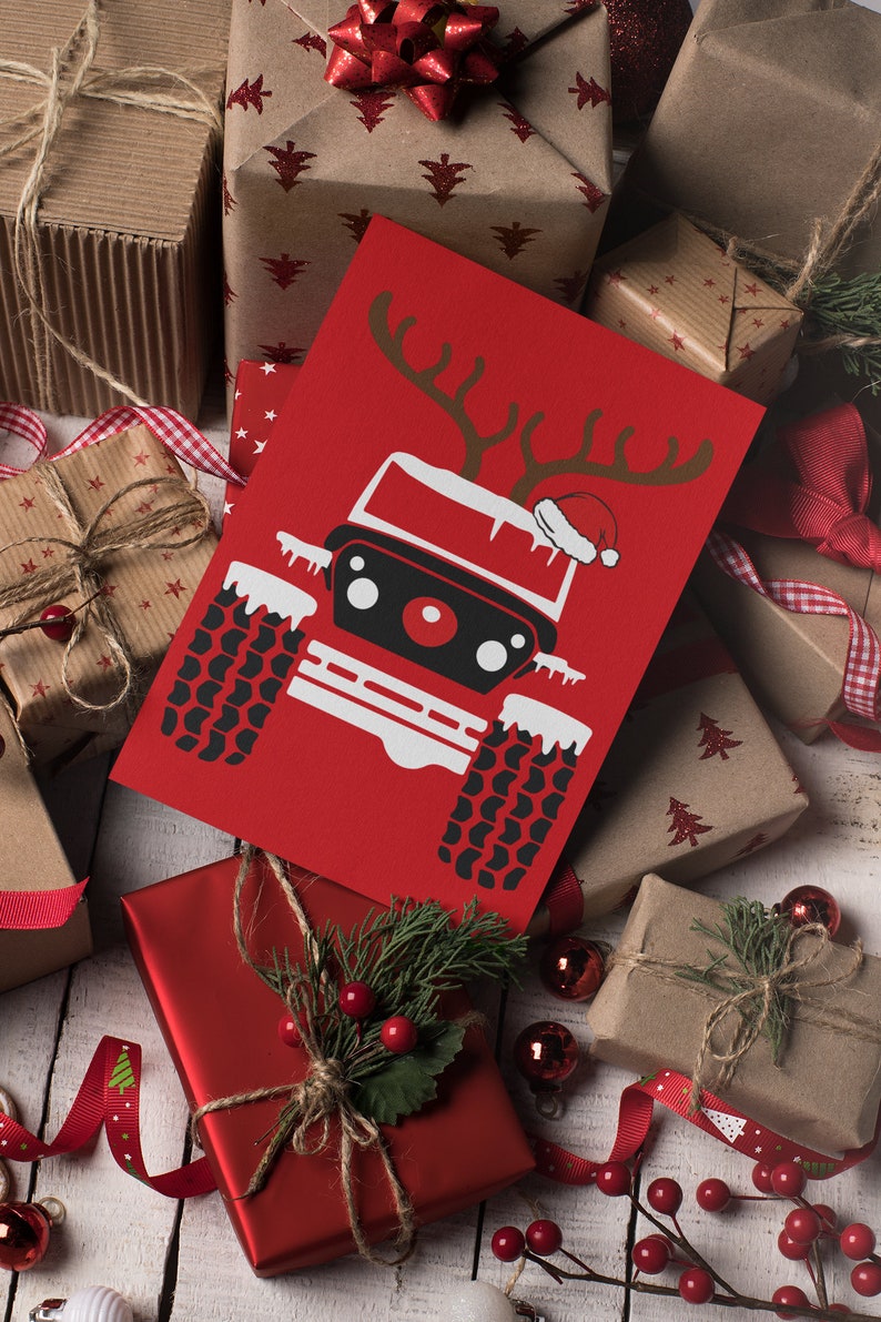 Puede incluir: Una tarjeta de Navidad roja con una ilustraci&oacute;n en blanco y negro de un jeep con cuernos de reno y un gorro de Pap&aacute; Noel. La tarjeta est&aacute; rodeada de regalos envueltos con papel rojo y marr&oacute;n y cinta roja.