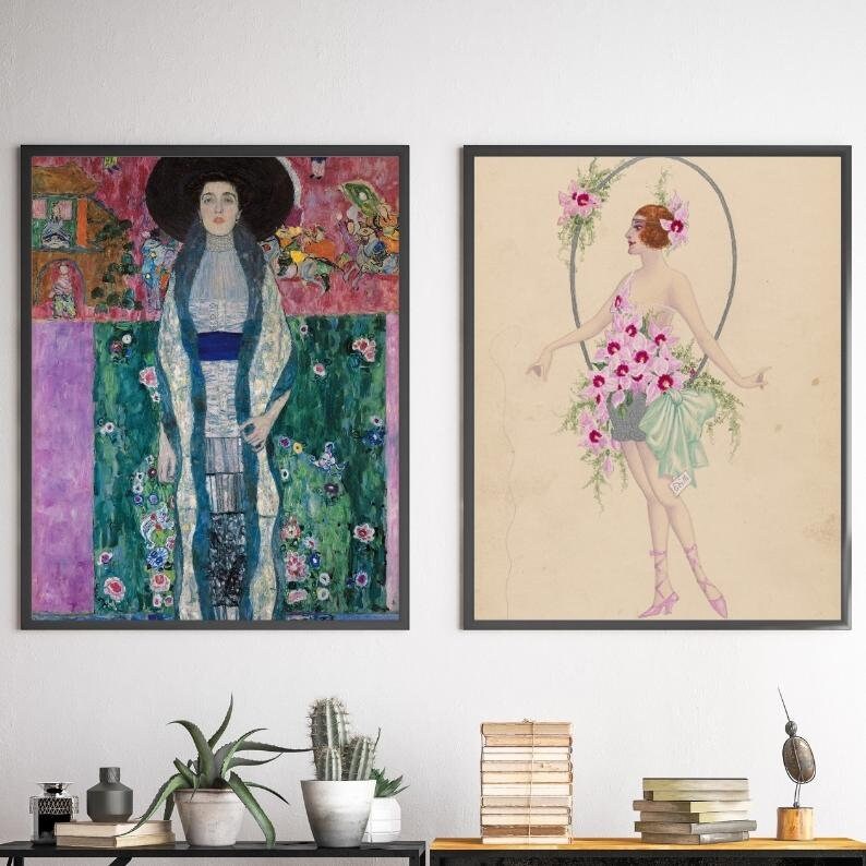 May include: Two framed art prints, one depicting a woman in a white dress with a blue sash standing in a garden, the other depicting a woman in a green dress with pink flowers.