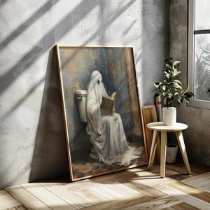 May include: A framed painting of a white ghost sitting on a toilet and reading a book. The ghost is wearing a white sheet and has a book in its hands. The painting is set against a light blue background.