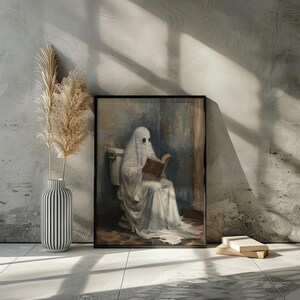 May include: A framed painting of a ghost sitting on a toilet and reading a book. The ghost is wearing a white sheet and has a book in its hands. The painting is set against a light blue background.