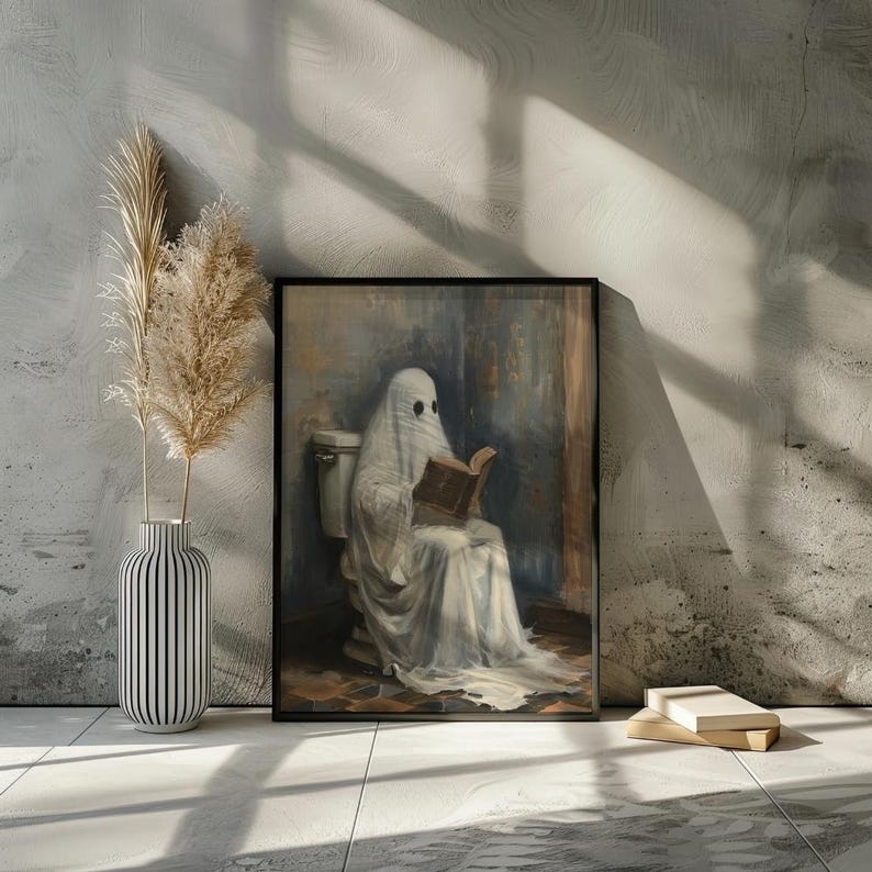 May include: A framed painting of a ghost sitting on a toilet and reading a book. The ghost is wearing a white sheet and has a book in its hands. The painting is set against a light blue background.