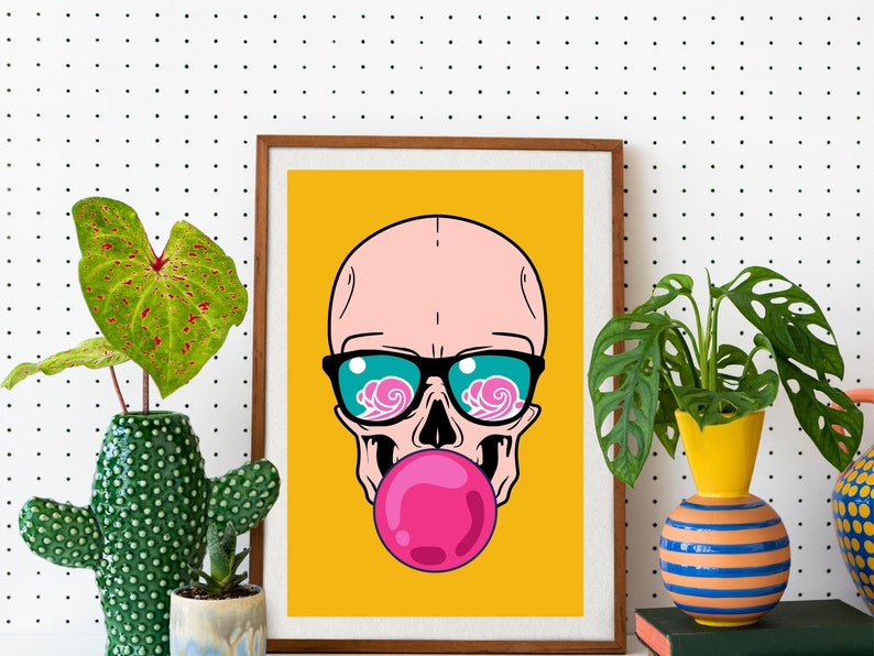 May include: A framed print of a cartoon skull wearing sunglasses and blowing a pink bubble. The background is yellow.