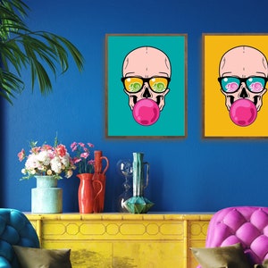 May include: Two framed illustrations of a skull wearing sunglasses and blowing a bubble. The skull in the left frame is on a turquoise background, and the skull in the right frame is on a yellow background.