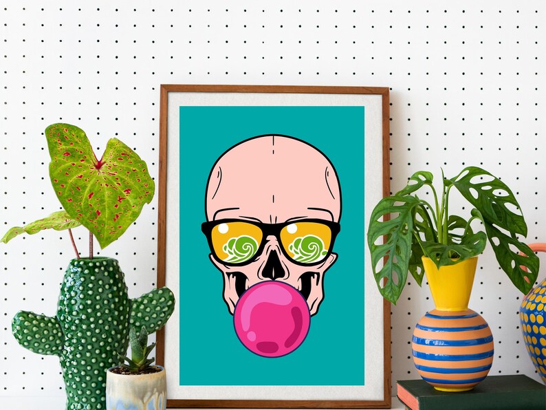 May include: A framed print of a cartoon skull wearing sunglasses with a pink bubblegum in its mouth. The background is a teal blue color.
