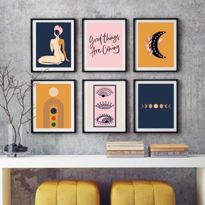 May include: Six black framed prints with various abstract designs. The prints feature a woman in a pink hat, a moon with a branch, a rainbow arch, three eyes, and a row of moons. The text "Good things are coming" is on one of the prints.