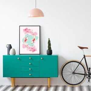 May include: A framed print of two koi fish swimming in a circle with pink cherry blossoms and a light blue background. The print is hanging on a teal blue dresser with four drawers. A potted plant and a bicycle are in the background.