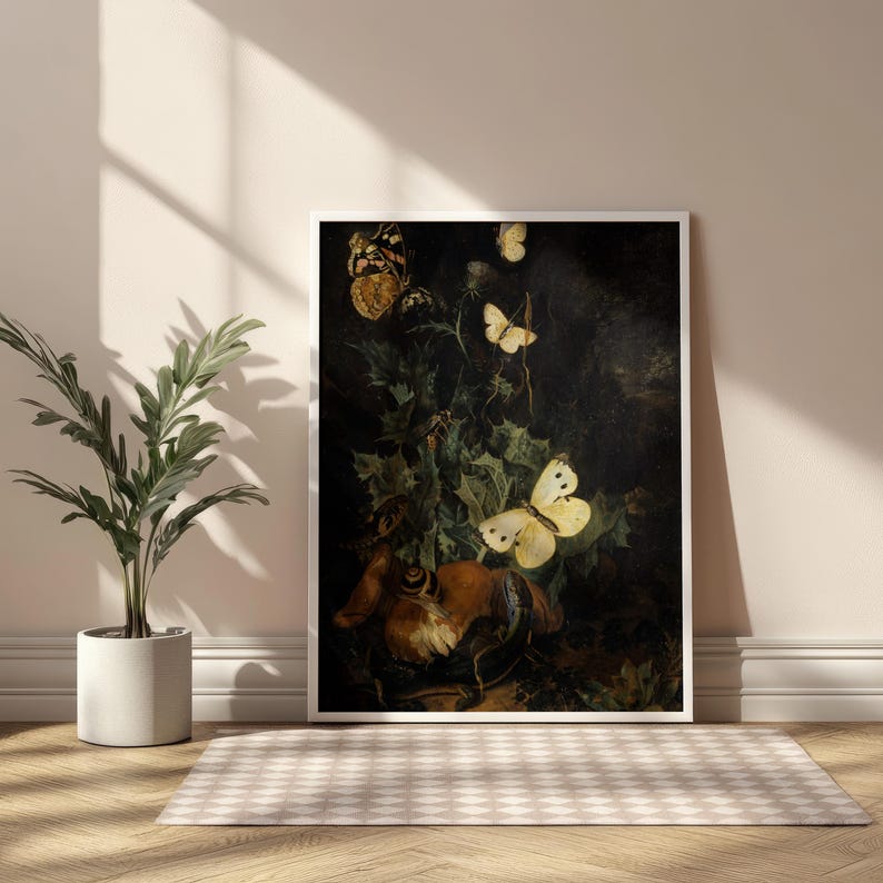 Op de afbeelding: Een ingelijste kunstdruk met een stilleven met vlinders. Het kunstwerk toont verschillende vlinders in tinten geel, bruin en wit, tegen een donkere achtergrond van gebladerte. De print wordt weergegeven in een witte lijst.