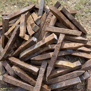 May include: A large pile of rusty metal wedges, likely used for splitting wood. The wedges are various sizes and shapes, with some showing signs of wear and tear.