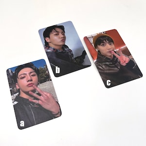 Peut inclure: Trois cartes photo représentant un jeune homme aux cheveux foncés. La première carte montre l'homme portant une veste noire et une chemise à carreaux rouge et noir. La deuxième carte montre l'homme portant une veste noire et une chemise blanche. La troisième carte montre l'homme portant une veste en cuir marron et un bonnet marron. Les cartes sont étiquetées avec les lettres a, b et c.