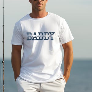 May include: White t-shirt with a blue "Daddy" graphic and the names "Jack", "Sophia", "Emily", and "John" printed below.