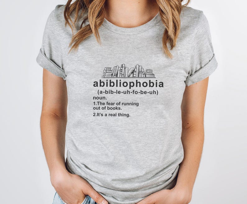 Pu&ograve; includere: Maglietta grigio chiaro con la parola "abibliophobia" stampata in nero, insieme alla sua pronuncia e definizione. La definizione recita: "La paura di rimanere senza libri. &Egrave; una cosa reale."