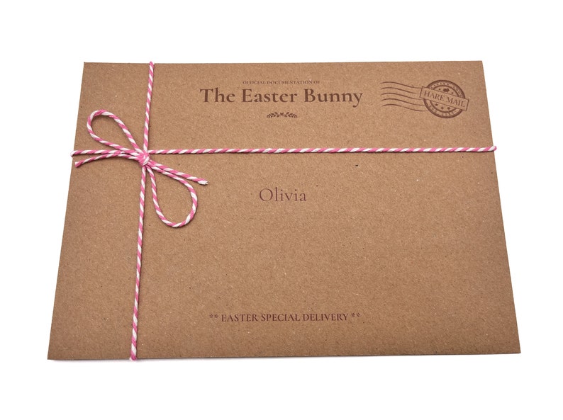 May include: A brown paper envelope with pink and white twine tied in a bow. The envelope has the text "The Easter Bunny" and "Olivia" printed on it. The envelope also has a stamp that says "Hare Mail".