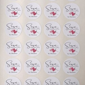 K&ouml;nnte beinhalten: Ein Bogen mit 24 wei&szlig;en runden Aufklebern mit einem rosa Herz und dem Text "Sewn with love by Charlotte". Der Text "24 Stickers Per Sheet" ist unten auf dem Bogen gedruckt.