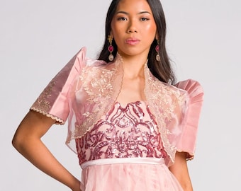 Könnte beinhalten: Ein hellrosa Kleid mit asymmetrischem Saum, einem Oberteil mit dunkelrosa Paillettenstickerei, einem mehrlagigen Tüllrock und einer passenden transparenten Bolerojacke mit kurzen, strukturierten Schmetterlingsärmeln und Goldstickerei.