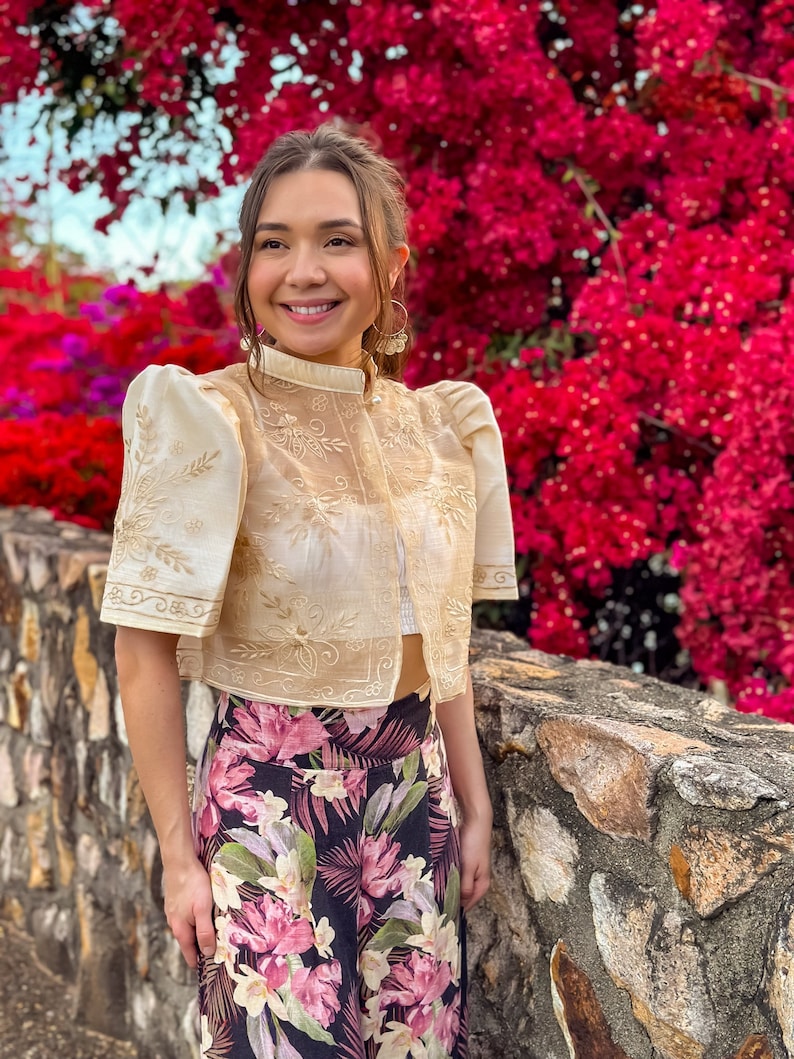 Our model is wearing 'Mutya' - a sheer, cream floral embroidered Mestiza Bolero with a high fashion collar and pearl-style button. It is worn like a blouse or outerwear over your favourite outfit.