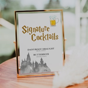 May include: A gold-framed sign with the text "Signature Cocktails" in a brown font. The sign features a watercolor illustration of Hogwarts castle and the text "Daisyroot Draught - Bridal Choice" and "Butterbeer - Groom's Choice".