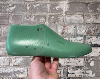 May include: A green plastic shoe last with the number 42 printed on it.