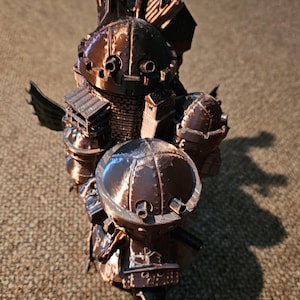 May include: A 3D printed model of a flying steampunk castle with multiple turrets, chimneys, and a large dome. The model is made of brown plastic and has a detailed design.
