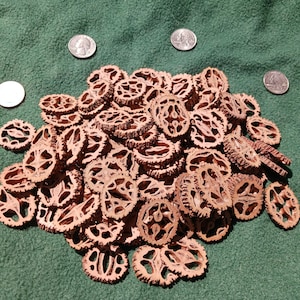 May include: A pile of approximately 100 brown, dried, and hollowed out walnut shells. The shells are arranged in a mound on a green felt surface. Four silver US quarters are placed around the pile of shells.