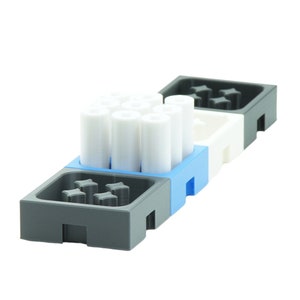 Könnte beinhalten: Ein Satz grauer, weißer und blauer Kunststoff-Aufbewahrungsbehälter mit weißen zylindrischen Gegenständen im Inneren. Die Behälter haben ein Gittermuster auf der Oberseite.