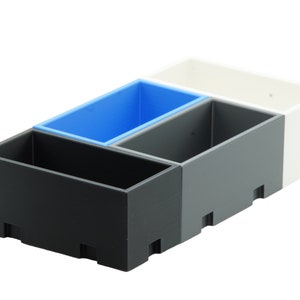 Könnte beinhalten: Drei rechteckige Aufbewahrungsbehälter, einer schwarz, einer grau und einer weiß, mit einem blauen Behälter, der in den grauen Behälter eingebettet ist.