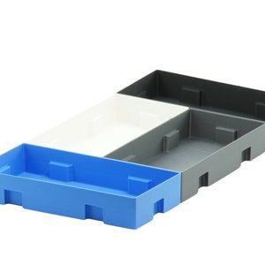 May include: Three plastic storage bins, one blue, one white and one grey, stacked on top of each other.
